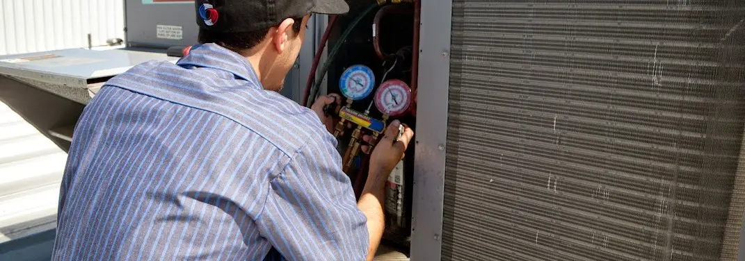 HVAC technician servicing a condenser unit in Weymouth Town